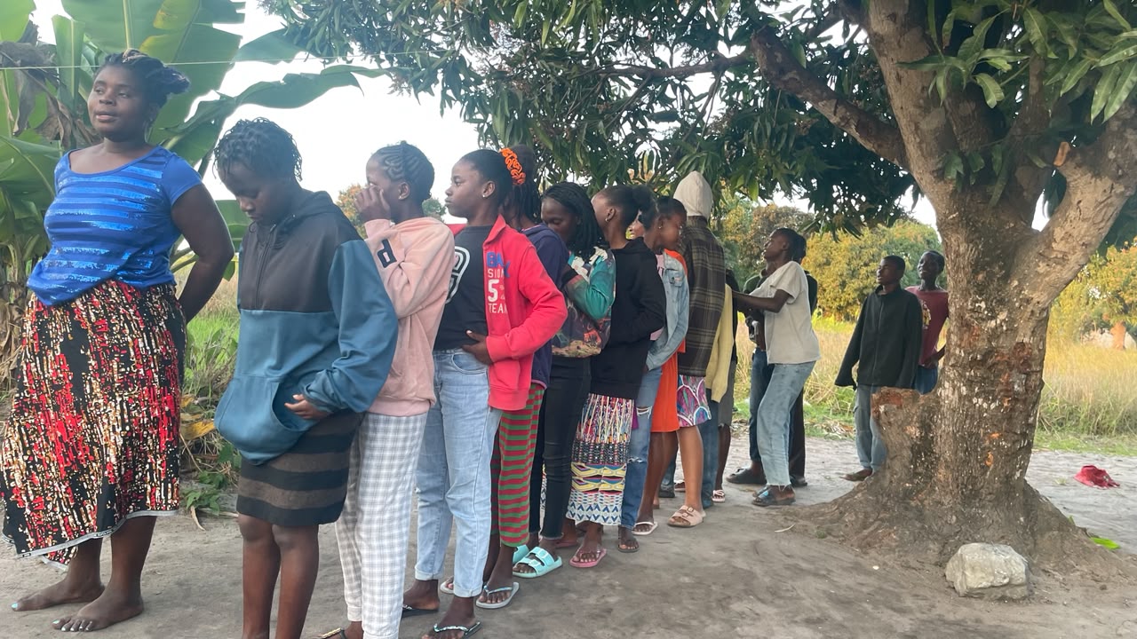 Jovens e adolescentes ensaiando sob uma árvore