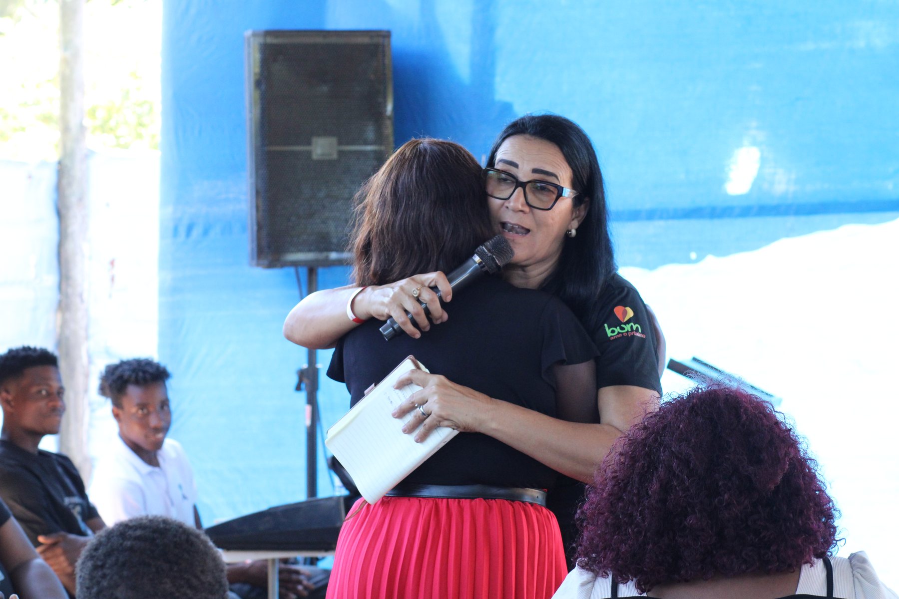 Missionária Ezir abraçando e orando com uma jovem