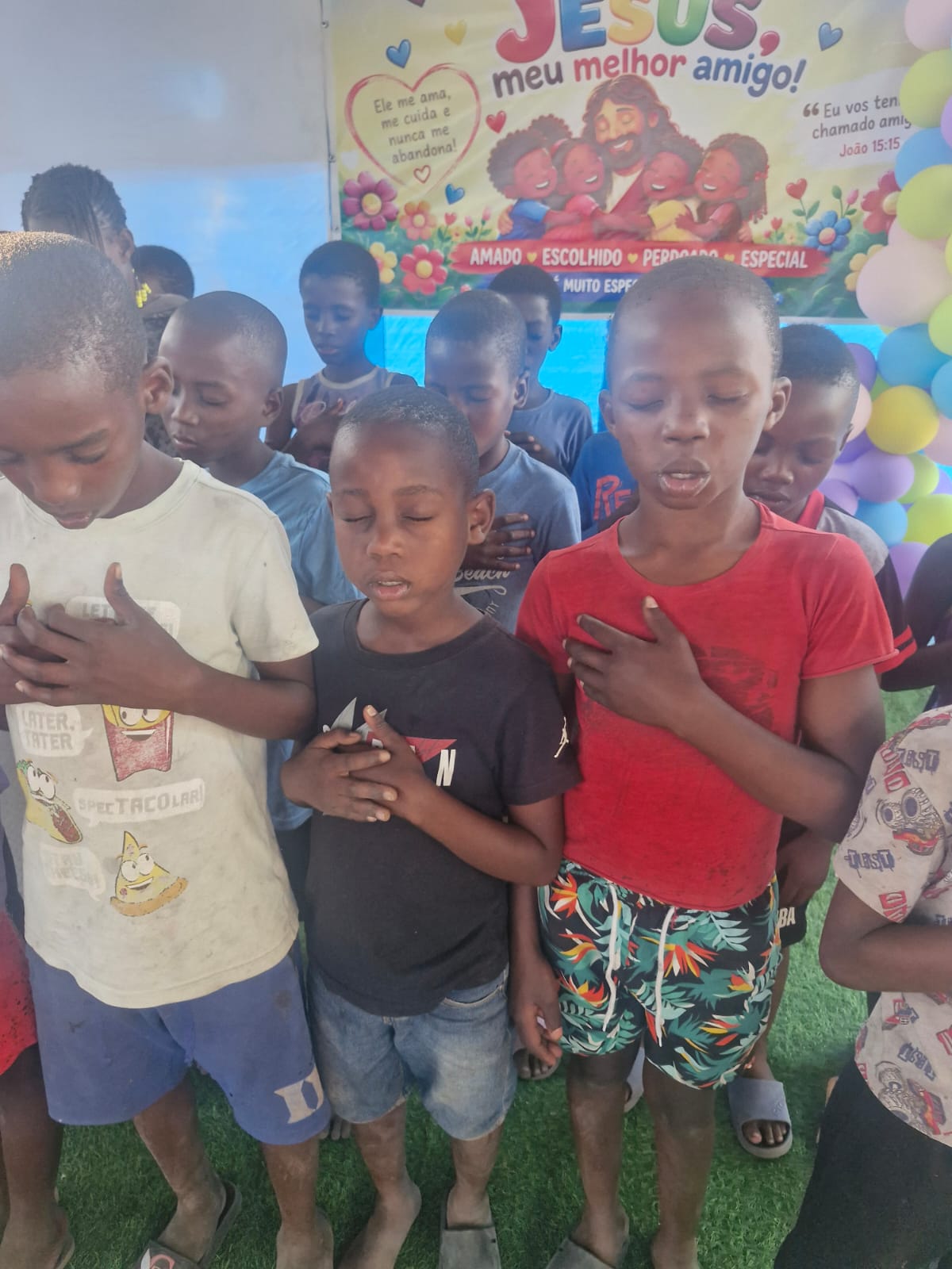 Crianças de olhos fechados e mãos erguidas durante um momento de decisão por Jesus